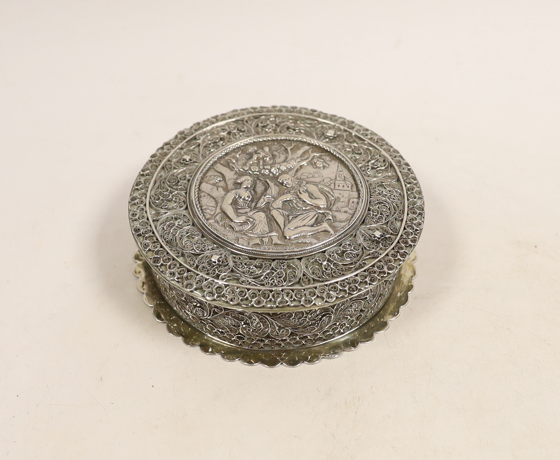 A continental white metal circular box and cover, with applied filigree decoration, diameter 11.2cm,