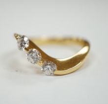 A modern 750 yellow metal and three stone diamond set crossover ring, size P, gross weight 5.4