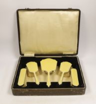 A cased George V silver and yellow guilloche enamel mounted five piece mirror and brush set, Hassett
