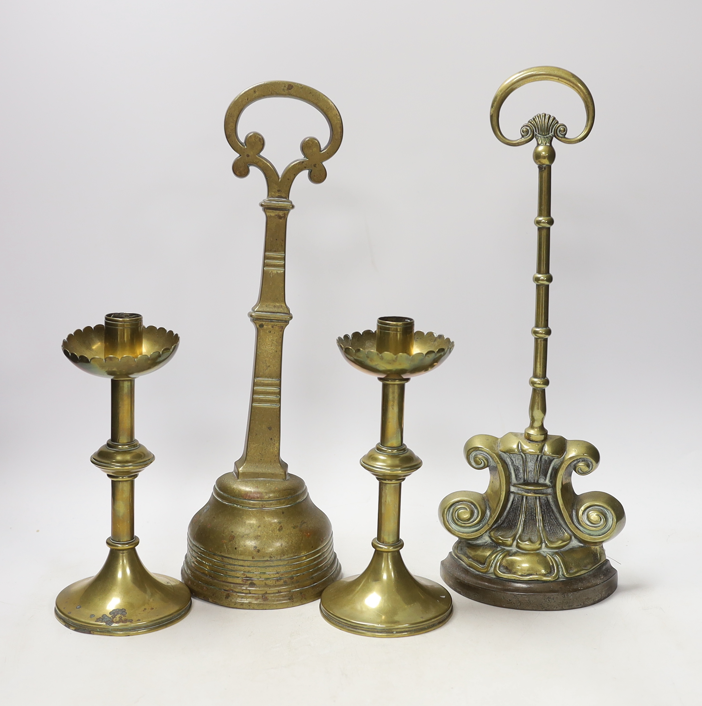 Two 19th century brass door porters and a pair of Gothic Revival brass candlesticks, 37cm (4)