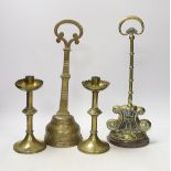 Two 19th century brass door porters and a pair of Gothic Revival brass candlesticks, 37cm (4)