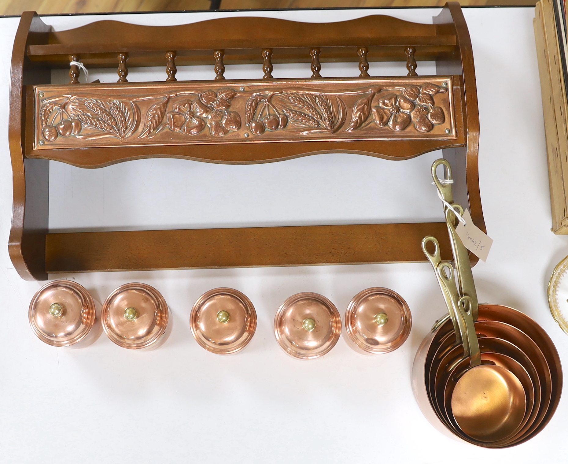 A graduated set of five French copper and brass saucepans and five lidded jars with copper mounted