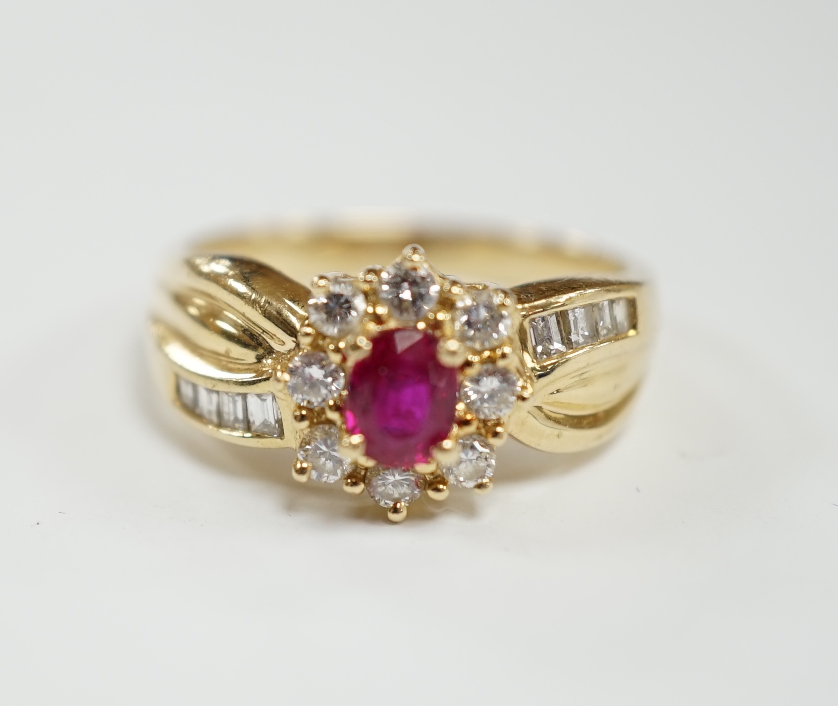 A modern 14k, ruby and diamond set oval cluster dress ring, with diamond chip set shoulders, size P,