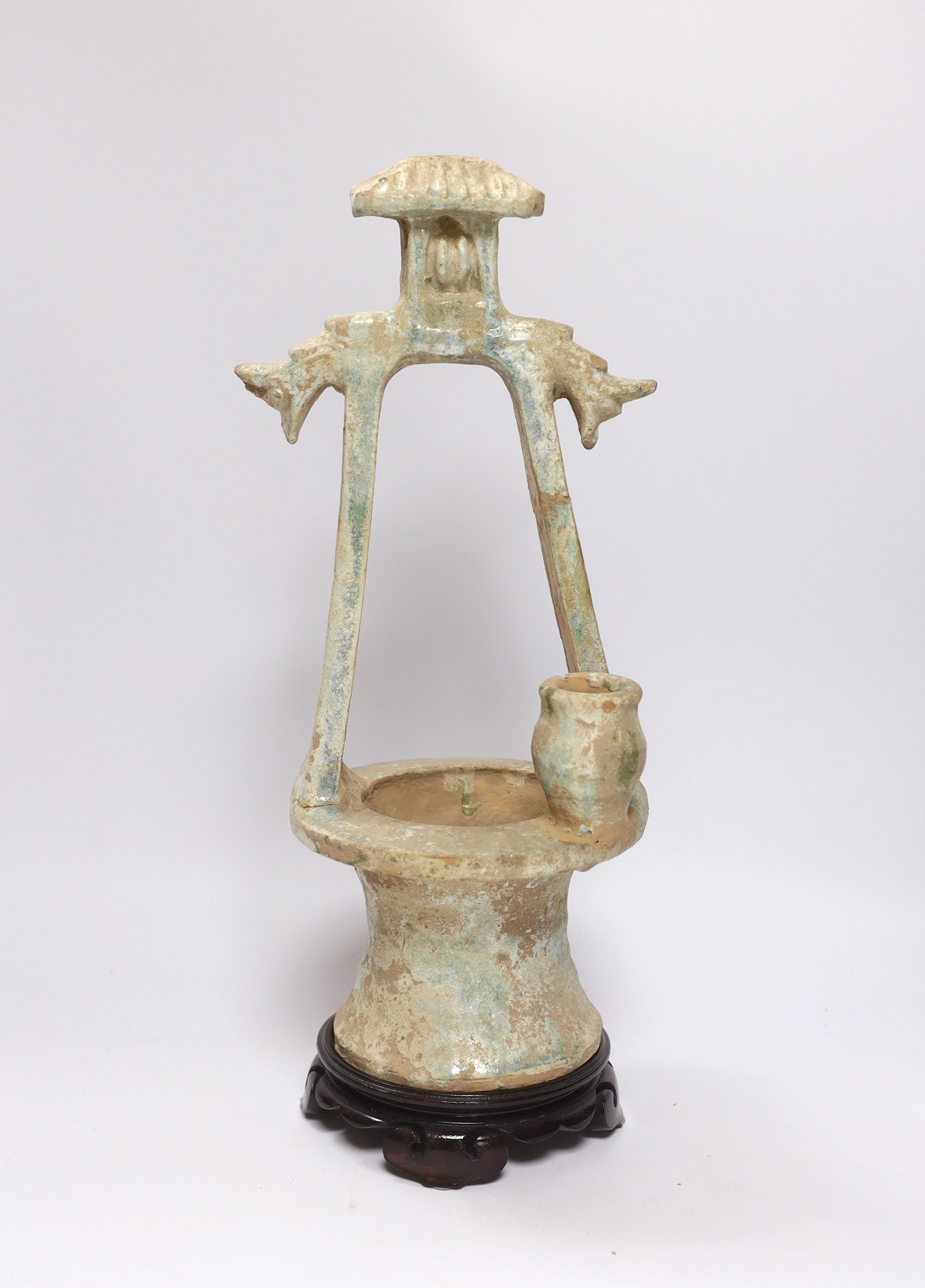 A Chinese glazed pottery model of a well, Han dynasty, with mineral iridescence, stand, 37cm high