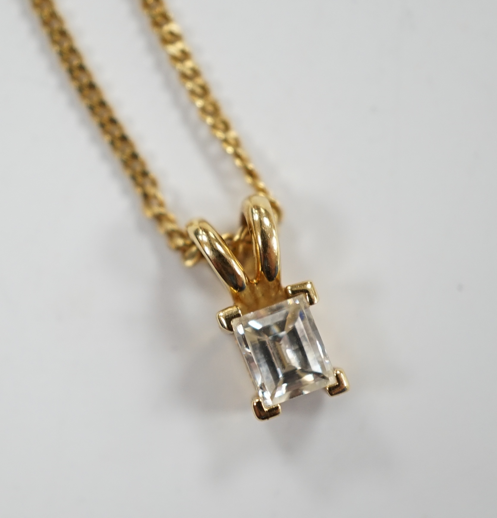 A modern 18ct gold and single stone fancy rectangular cut diamond set pendant, 9mm, on an 18ct