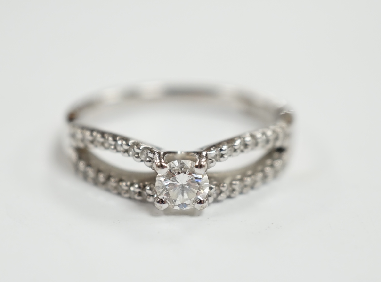 A modern 18ct white gold and single stone diamond set ring, with diamond chip set split shoulders,