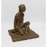 An abstract bronzed resin sculpture of a kneeling man, 30cm