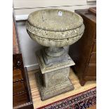 A set of three circular reconstituted stone garden urns on square plinths, diameter 54cm, height