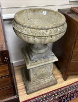 A set of three circular reconstituted stone garden urns on square plinths, diameter 54cm, height