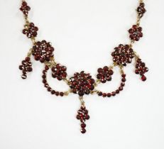 An early 20th century gilt sterling and garnet cluster set drop necklace, 45cm.