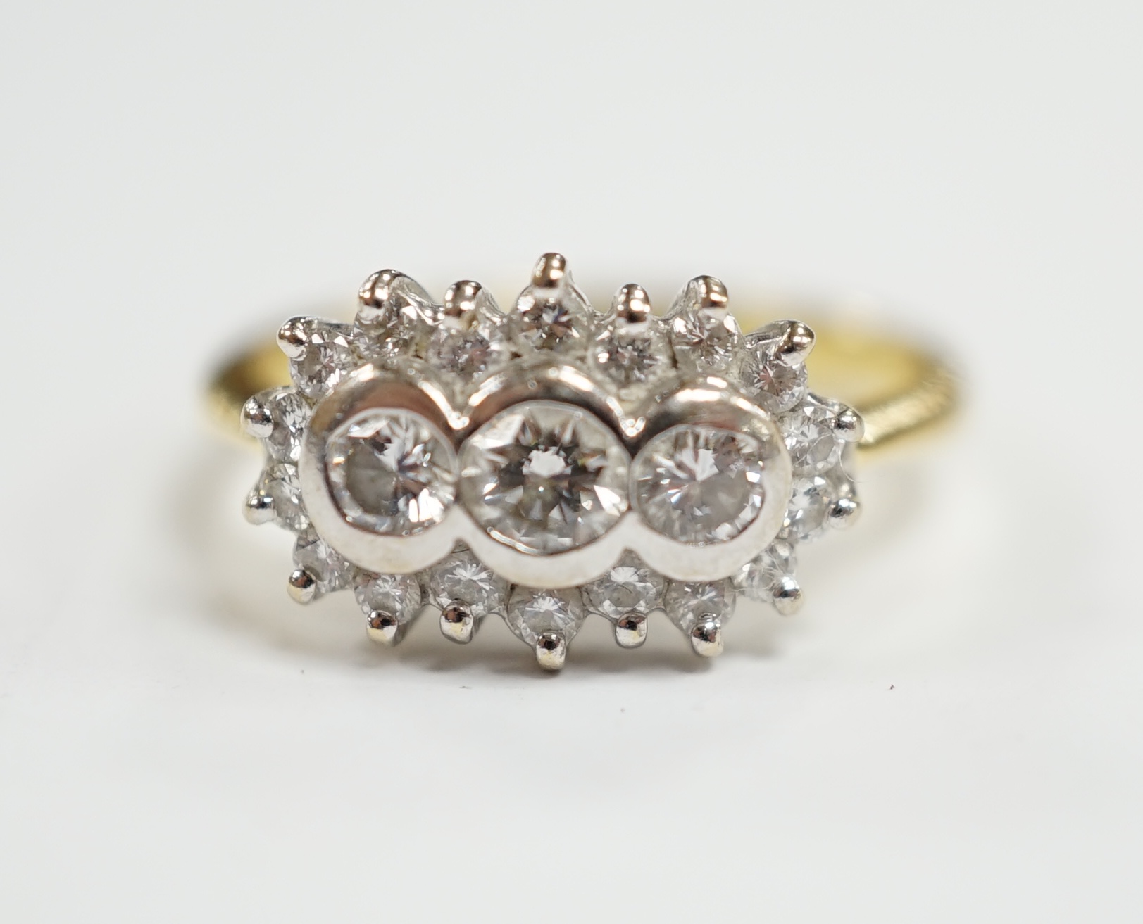 A modern 18ct gold and collet set three stone diamond ring, with diamond chip set border, size J/