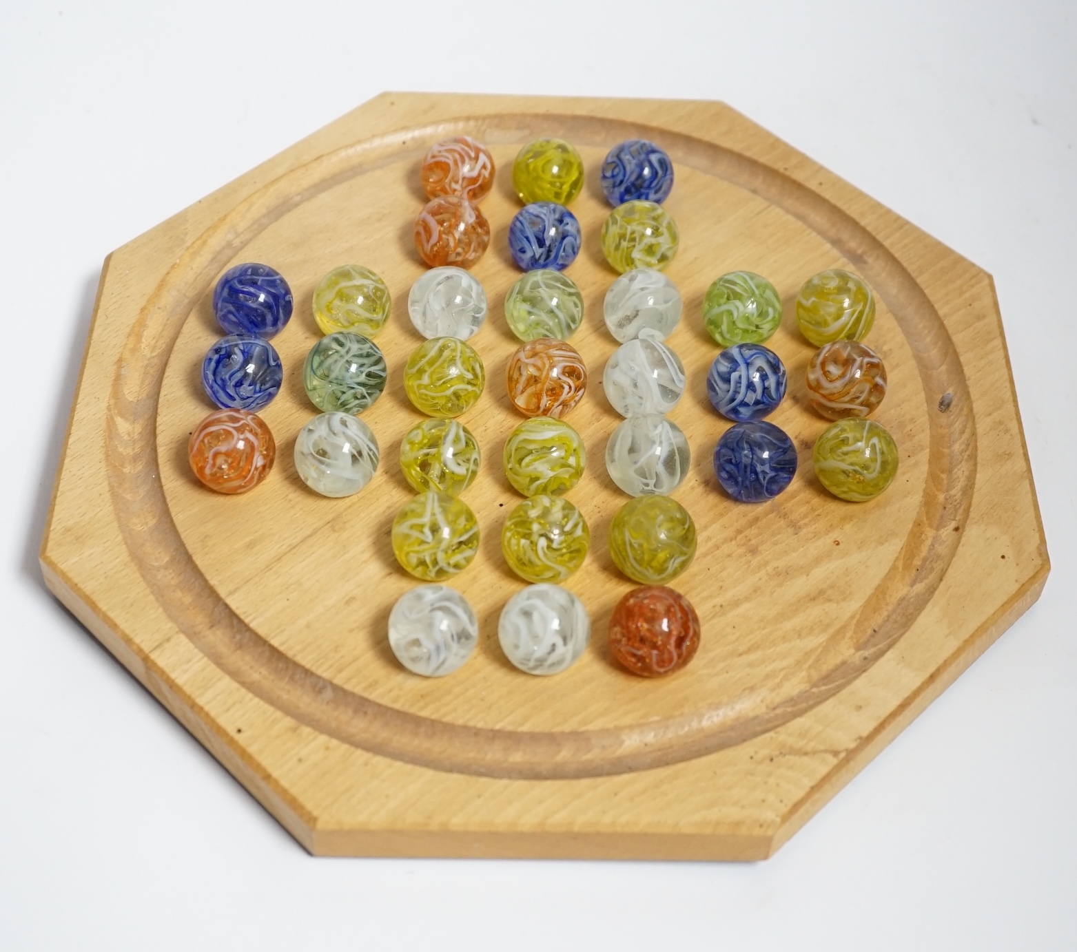 A turned wood solitaire board with multi-coloured glass marbles, 27cm wide