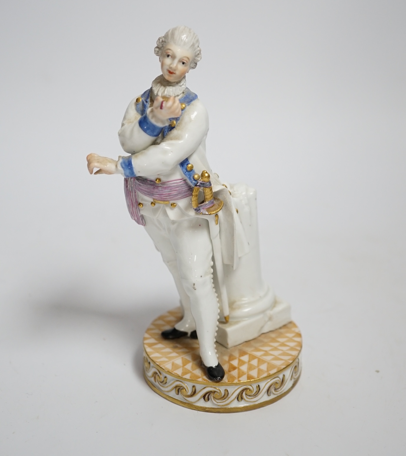 A Meissen style porcelain figure of a soldier in dress uniform with sword and holding aloft a pocket