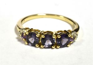 9KT GOLD, PURPLE SAPPHIRE THREE STONE DRESS RING The ring with diamond accent shoulders, ring size N