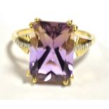 10K GEM SET COCKTAIL RING The ring set with a step cut purple gem measuring 15 x 10mm, Clear stone
