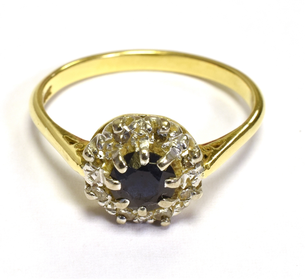 18CT SAPPHIRE & DIAMOND HALO RING Dark blue round cut sapphire, surrounded by a halo of grain set,