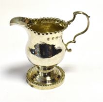GEORGE III SILVER CREAM JUG With a baluster shaped body on a pedestal foot with pie crust rim.