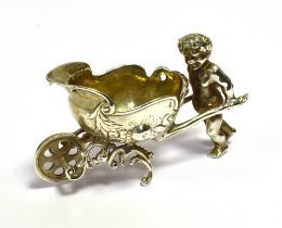 CONTINENTAL SILVER PLATED SALT In the form of an Amorini pushing an embossed barrow with parcel gilt