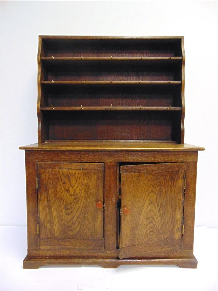 A HAND-MADE MINIATURE OAK DRESSER circa 1954, comprising a rack of three shelves, with an enclosed