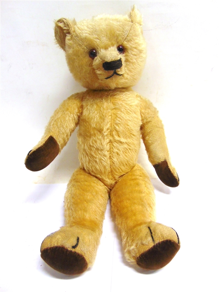 A GOLD MOHAIR TEDDY BEAR mid 20th century, with orange glass eyes, a dark brown horizontally