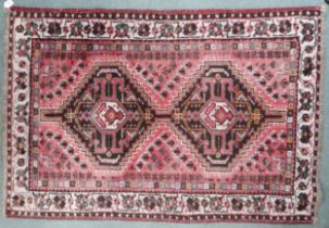 A pink ground Heriz rug with multicoloured geometric medallions within cream borders, 152cm long x