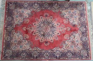 A terracotta ground Tabriz style rug with cream and blue central medallion, matching spandrels and