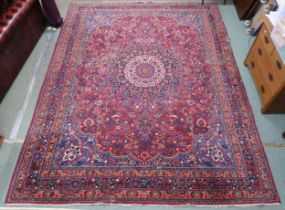 A red floral patterned ground Tabriz rug with sunburst central medallion, blue spandrels and