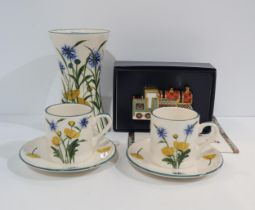 A Griselda Hill buttercup and cornflower pattern vase with a pair of matching coffee cans and