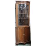 A 20th century mahogany bow front glazed corner cabinet with glazed door over pair of cabinet doors,