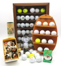 A collection of golf balls, housed over a wall mounted rack and a glazed display case, including six