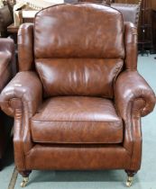 A contemporary Thomas Lloyd brown leather armchair with scrolled arms on turned front supports