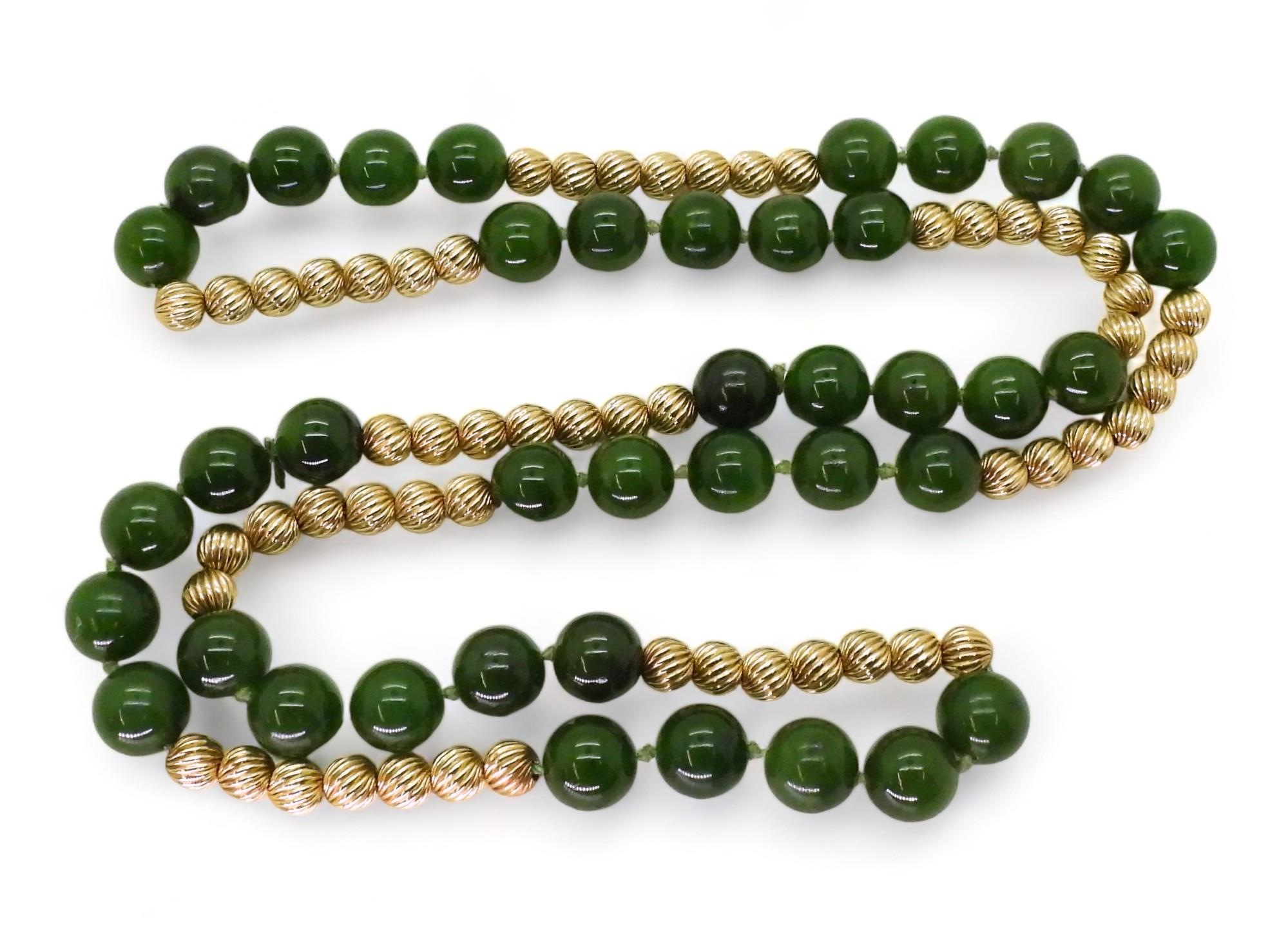 A long string of nephrite beads (each 10mm) and yellow metal twisted pattern beads (approx 6mm),