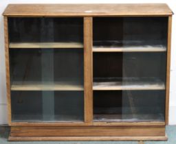 An early to mid 20th century oak bookcase with two pairs of glass sliding doors, 80cm high x 100cm