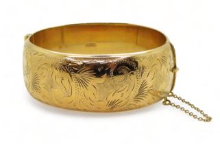 A 9ct gold wide engraved hollow bangle, inner diameter 6cm x 5.5cm, 2.4cm wide, weight 34.4gms