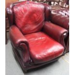 A contemporary Thomas Lloyd oxblood leather armchair with scrolled arms on turned front supports