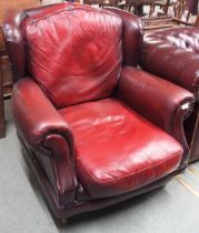 A contemporary Thomas Lloyd oxblood leather armchair with scrolled arms on turned front supports