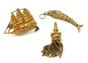 Three gold and yellow metal charms to include a articulated fish with a pearl in its mouth and red