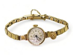 A 9ct gold ladies Record watch and strap, circa 1962 with attached St. Christopher, weight including
