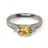 A platinum, yellow sapphire and diamond ring, set with a 6mm round cut sapphire, and 0.50cts of