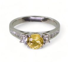 A platinum, yellow sapphire and diamond ring, set with a 6mm round cut sapphire, and 0.50cts of