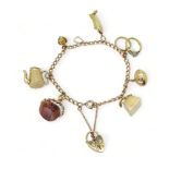 A 9ct gold charm bracelet with seven attached 9ct gold and yellow metal charms to include a speed