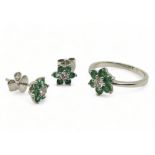 A 14k white gold emerald and diamond flower ring, size O, with matching earrings, set with estimated