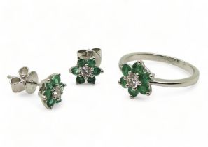 A 14k white gold emerald and diamond flower ring, size O, with matching earrings, set with estimated