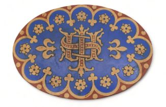 A Minton encaustic tile of oval shape with central initials surrounded by flowers and arched