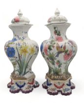A pair of Le Nove faience glazed jars and covers on stands, painted with flowers and birds Condition