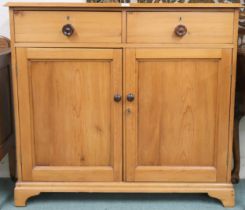 An early 20th century pine cabinet with two short drawers over pair of panel cabinet doors on plinth