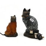 A glass and metal cat lamp with black and white mottled effect and another in amber glass