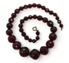 A string of faceted cherry amber coloured beads, the largest is 18.5mm, and the smallest 7.3mm,