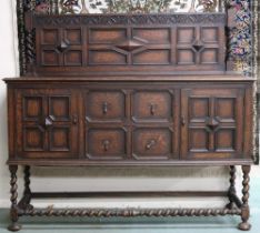 An early 20th century oak Jacobean style sideboard with carved panelled backsplash over pair of