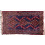A dark blue ground Balouch style rug with diamond medallions on geometric patterned ground and red